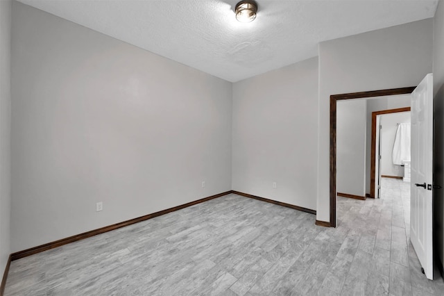 unfurnished room with a textured ceiling and light hardwood / wood-style floors