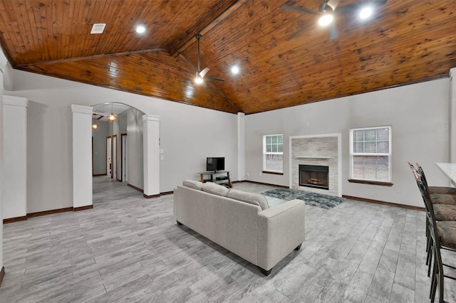 living room with a tile fireplace, high vaulted ceiling, light hardwood / wood-style flooring, ceiling fan, and ornate columns