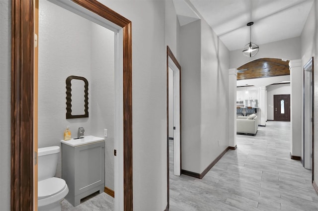 corridor with sink, light hardwood / wood-style flooring, and decorative columns