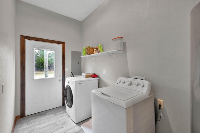 laundry area with electric panel, light hardwood / wood-style flooring, and independent washer and dryer