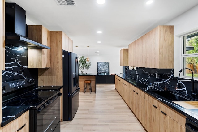 kitchen featuring pendant lighting, sink, light hardwood / wood-style floors, wall chimney range hood, and black appliances