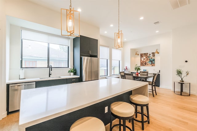 kitchen featuring pendant lighting, a center island, sink, and appliances with stainless steel finishes