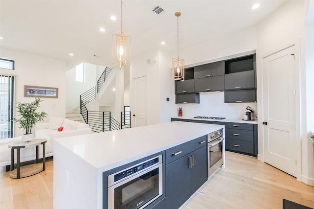 kitchen featuring a center island, stainless steel oven, hanging light fixtures, and light hardwood / wood-style floors