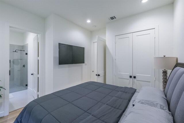 bedroom with connected bathroom, light hardwood / wood-style floors, and a closet