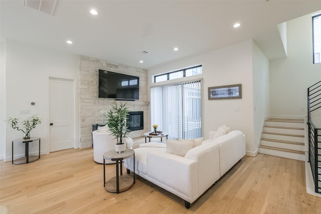 living room with a stone fireplace and light wood-type flooring