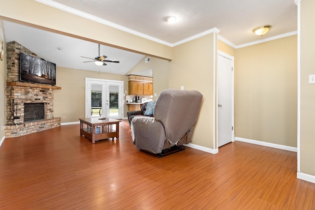 living room with french doors, ceiling fan, a fireplace, hardwood / wood-style floors, and lofted ceiling