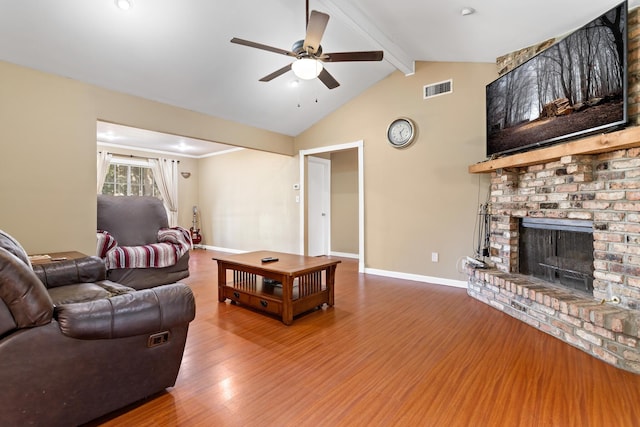 living room with vaulted ceiling with beams, ceiling fan, hardwood / wood-style flooring, and a brick fireplace