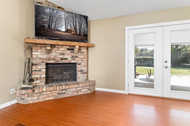 unfurnished living room with french doors, a brick fireplace, and hardwood / wood-style floors