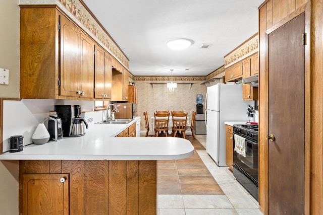 kitchen with kitchen peninsula, sink, black range, and light tile patterned floors