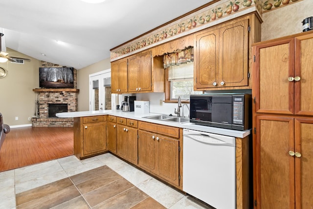 kitchen featuring kitchen peninsula, white dishwasher, sink, a fireplace, and lofted ceiling