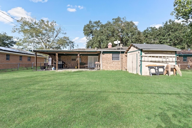 back of house featuring a lawn, a storage unit, and a patio area