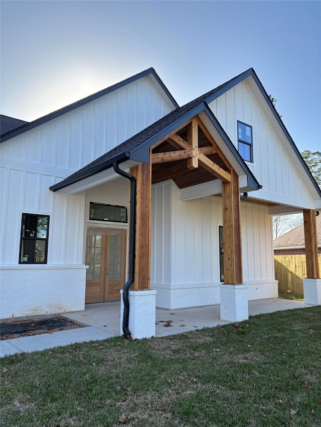 view of front facade featuring french doors, board and batten siding, and a front lawn