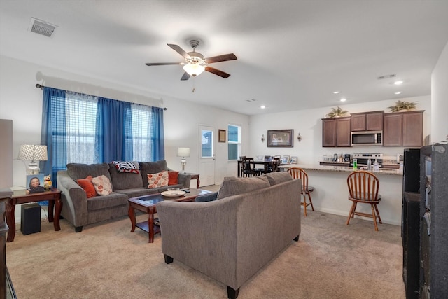 carpeted living room with ceiling fan