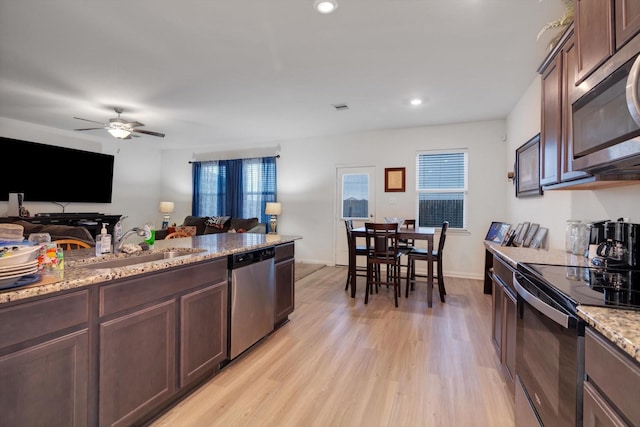 kitchen with ceiling fan, sink, light stone countertops, light hardwood / wood-style floors, and appliances with stainless steel finishes