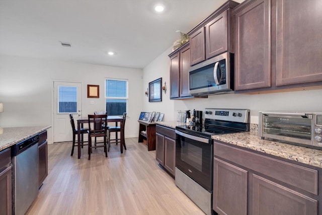 kitchen featuring dark brown cabinetry, light stone counters, light hardwood / wood-style flooring, and stainless steel appliances