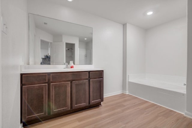 bathroom featuring vanity, a bath, and wood-type flooring