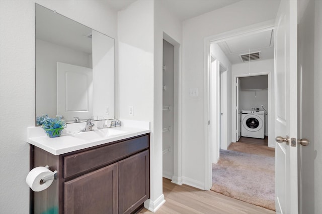 bathroom with hardwood / wood-style floors, vanity, and washer / dryer