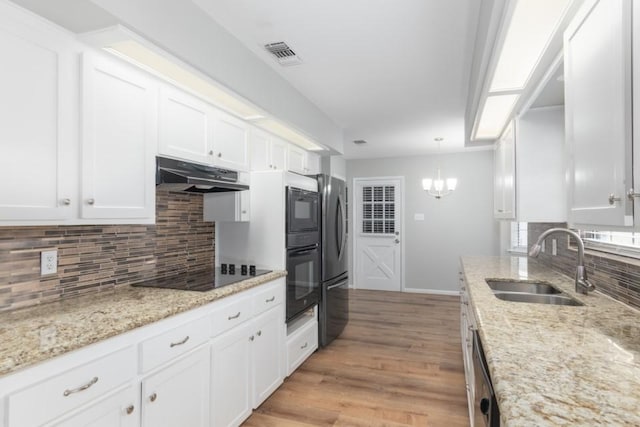 kitchen featuring decorative light fixtures, sink, appliances with stainless steel finishes, white cabinets, and light stone counters