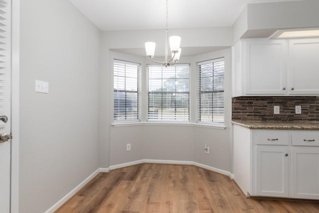 unfurnished dining area with light wood-type flooring and a notable chandelier