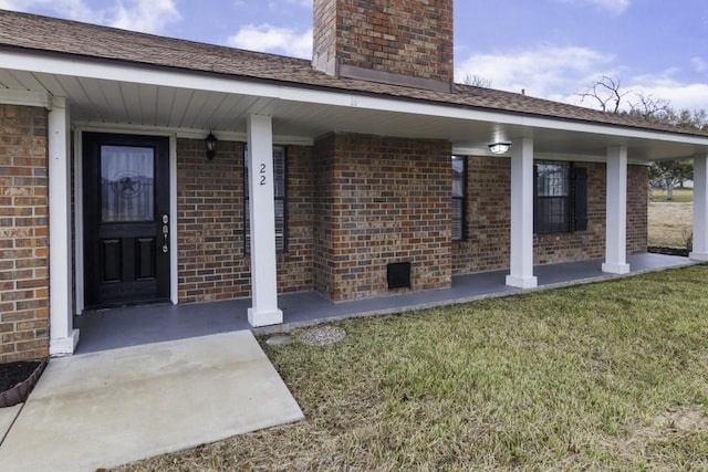 view of exterior entry featuring covered porch and a yard