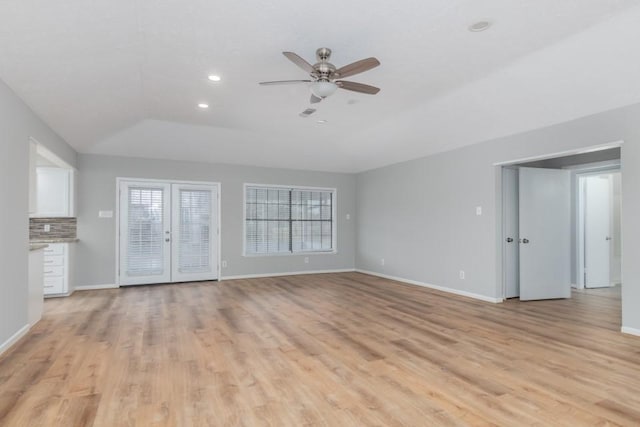 unfurnished living room featuring vaulted ceiling, ceiling fan, light hardwood / wood-style flooring, and french doors