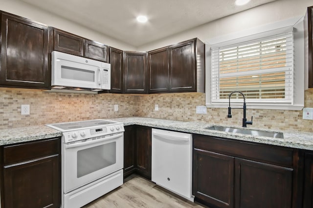 kitchen with sink, white appliances, backsplash, dark brown cabinetry, and light wood-type flooring