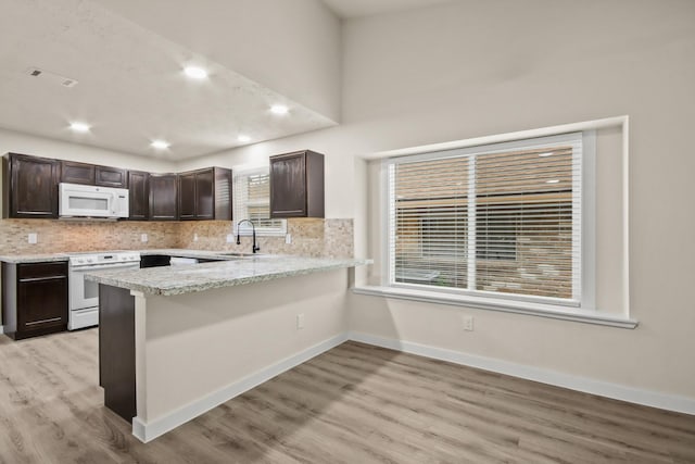 kitchen featuring dark brown cabinetry, sink, white appliances, and kitchen peninsula