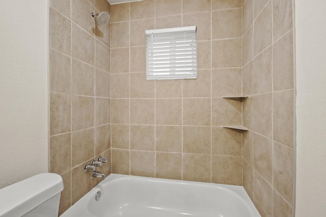 bathroom featuring tiled shower / bath and toilet