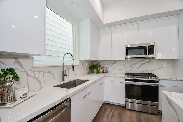 kitchen featuring sink, decorative backsplash, light stone counters, white cabinetry, and stainless steel appliances