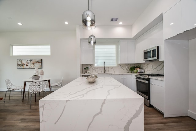 kitchen with white cabinets, appliances with stainless steel finishes, pendant lighting, and sink