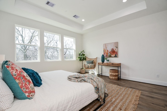 bedroom featuring a raised ceiling and dark hardwood / wood-style floors