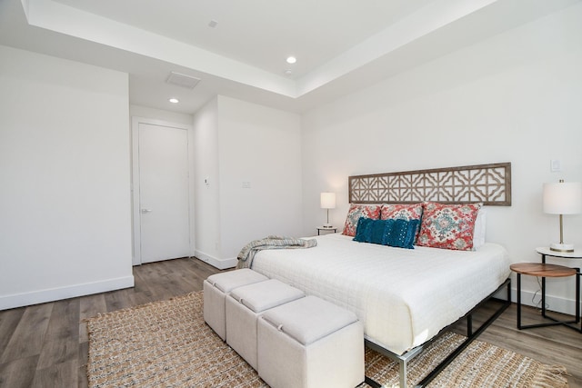 bedroom featuring wood-type flooring and a tray ceiling