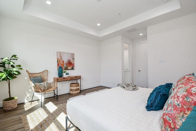 bedroom featuring a raised ceiling and dark hardwood / wood-style flooring