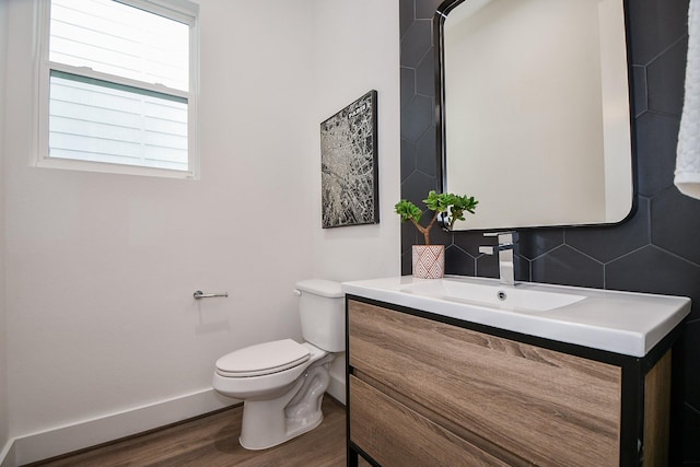 bathroom featuring wood-type flooring, vanity, tasteful backsplash, and toilet