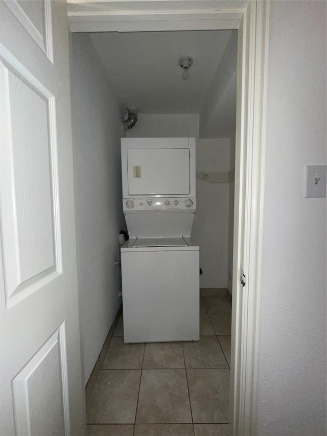 clothes washing area featuring light tile patterned floors and stacked washer and dryer