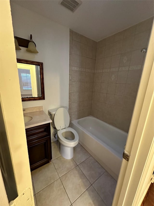 full bathroom with tile patterned floors, tiled shower / bath, vanity, and toilet