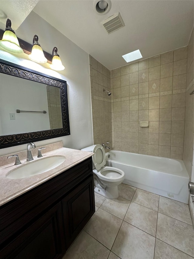 full bathroom with a skylight, tile patterned flooring, toilet, vanity, and tiled shower / bath