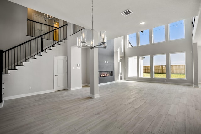 unfurnished living room with a towering ceiling, a tile fireplace, and a chandelier