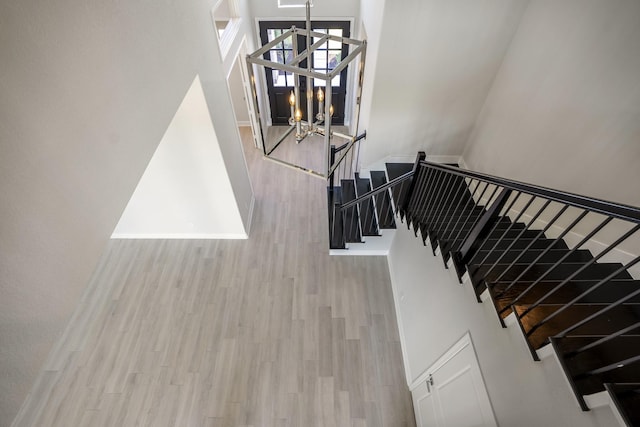 stairway featuring hardwood / wood-style flooring, a high ceiling, and a chandelier