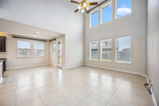 unfurnished living room featuring ceiling fan, light tile patterned floors, and a high ceiling