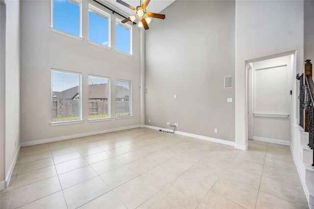 unfurnished living room with ceiling fan, a high ceiling, a wealth of natural light, and light tile patterned floors