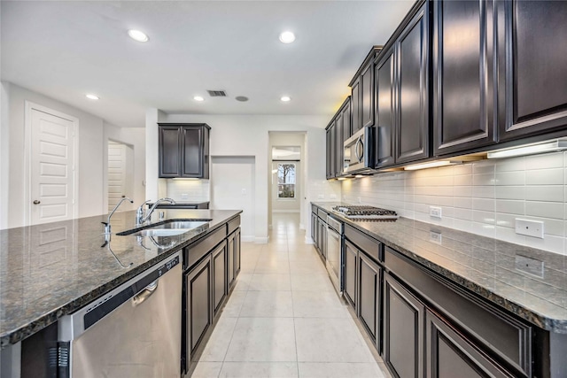 kitchen with sink, appliances with stainless steel finishes, a center island with sink, and light tile patterned flooring