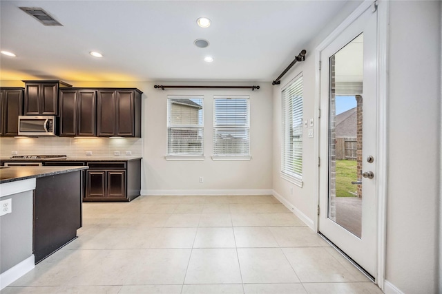 kitchen with light tile patterned floors, backsplash, and dark brown cabinetry