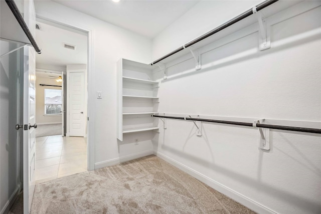 walk in closet with ceiling fan and light colored carpet