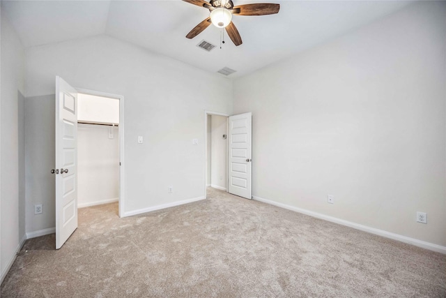 unfurnished bedroom featuring ceiling fan, a closet, lofted ceiling, light colored carpet, and a walk in closet