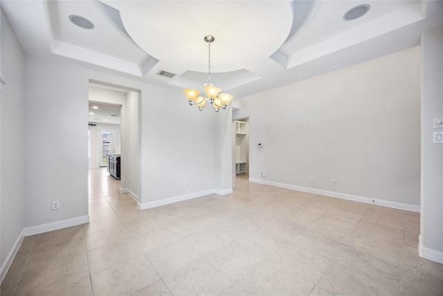 tiled empty room with a tray ceiling and an inviting chandelier