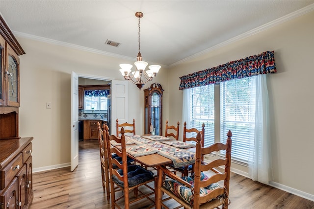 dining space with a wealth of natural light, crown molding, light hardwood / wood-style floors, and an inviting chandelier