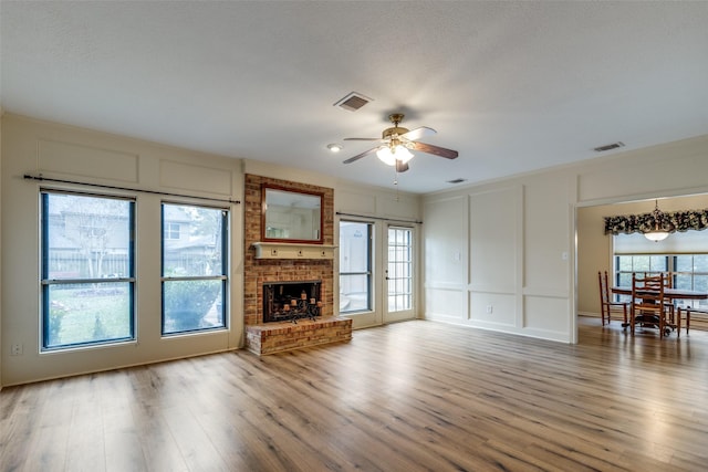 unfurnished living room featuring hardwood / wood-style flooring, a brick fireplace, and ceiling fan