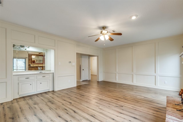 unfurnished living room with light hardwood / wood-style flooring, ceiling fan, and sink