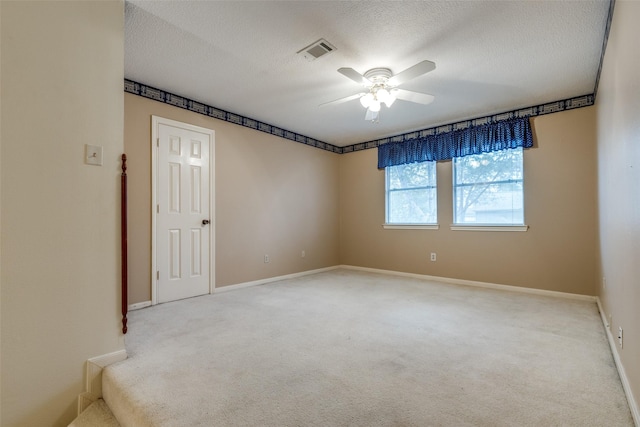 unfurnished room with ceiling fan, a textured ceiling, and light carpet